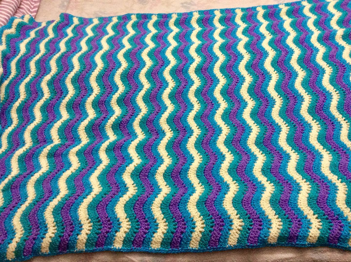 Colourful crocheted afghan with wave pattern.